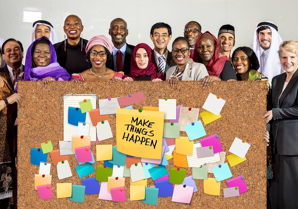 Photo of lots of people behind a noticeboard that says Make Things Happen